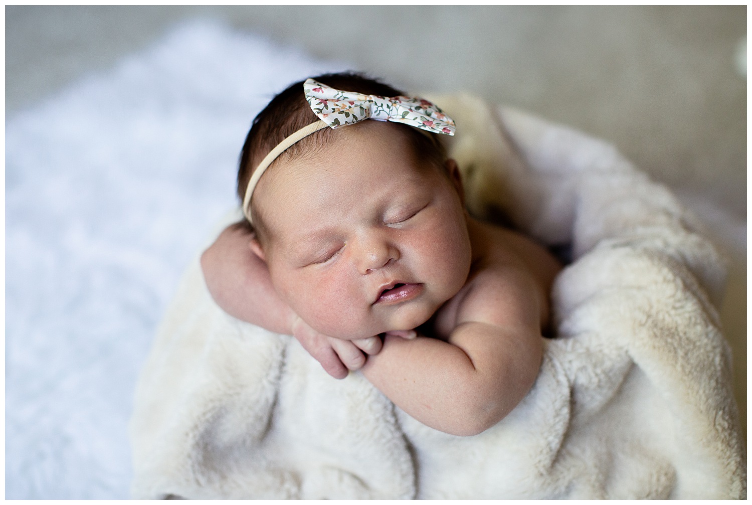  Newborn baby girl sleeping in a bucket with a head band on her head posing for newborn photos in Carmel, Indiana 